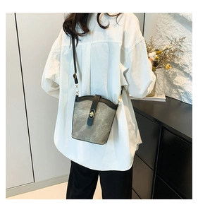 Detail view of retro bucket bag with gold twist lock and adjustable shoulder strap on model