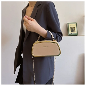 Dettaglio di un'elegante borsa beige a scatola con catena dorata su una modella