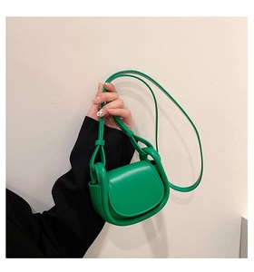 Detail of vibrant green leather saddle bag featuring a curved silhouette and smooth finish