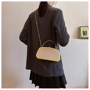 Borsa a trapezio beige con bordi gialli e tracolla a catena dorata su modella