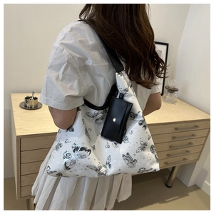 Vue détaillée du sac cabas blanc en similicuir avec motif papillon noir et pochette latérale