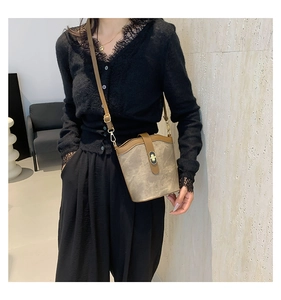 Detail of retro bucket bag featuring turn-lock closure and contrast leather textures