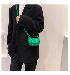 Detail of a vibrant green mini saddle bag with smooth leather finish and thin shoulder strap
