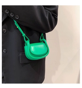 Detail of neon green mini leather saddle bag with rounded flap and long shoulder strap