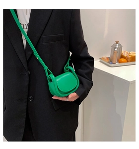 Detail view of mini bright green leather crossbody bag with semi-circle flap and silver rings