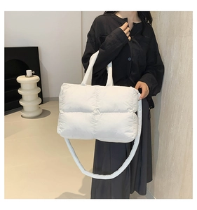 Detail of white quilted puffer tote bag showing soft padded handles and texture