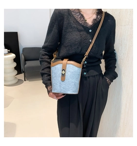 Detail of light blue bucket bag with brown leather trim and golden twist lock closure