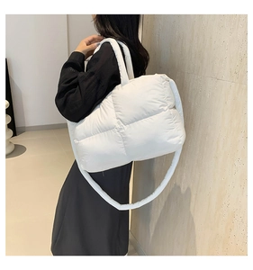 White quilted puffer bag with wide strap worn by a model in a minimalist setting