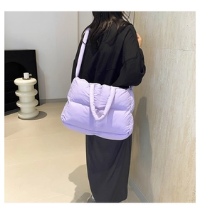 Padded purple quilted tote bag shown on shoulder in a minimalist indoor setting
