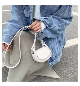 Detailed view of a white vintage mini saddle bag with smooth texture and leather strap