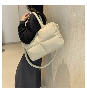 Quilted puffer tote bag in cream nylon with puffy straps on a minimalist background