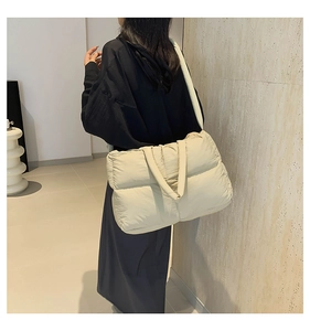 Close-up of beige quilted puffy tote bag showing soft texture and shoulder strap details