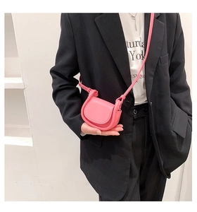 Detail of pink micro crossbody bag in smooth leather worn by a model in a black suit