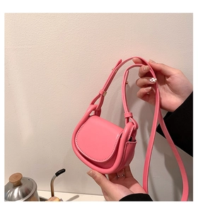 Detailed shot of a mini pink saddle bag with golden hardware and adjustable strap