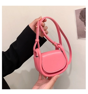 Detailed view of a pink faux leather mini saddle bag with an adjustable shoulder strap