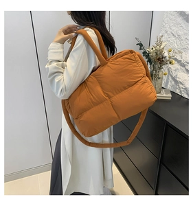 Detail of large orange quilted tote bag featuring padded handles and puffy grid texture