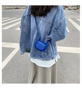 Blue mini saddle bag shown on a model wearing denim jacket in a street view