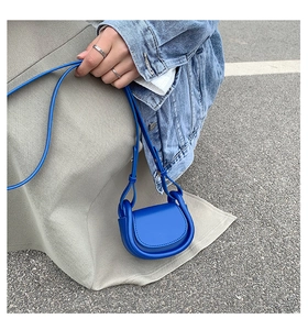 Outdoor close-up of a bright blue faux leather saddle crossbody bag for kids