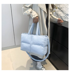 Quilted light blue padded tote bag shown with an adjustable shoulder strap and hand grip