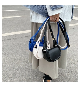 Detail of mini saddle bag in blue, cream, and black colors with adjustable shoulder straps
