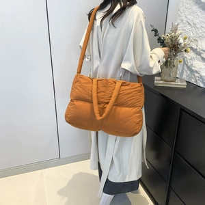 Bright orange quilted tote bag with large capacity shown in a stylish indoor setting