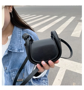 Close-up of a mini black saddle bag in smooth leather with thick ring strap connectors