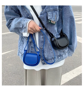 Outdoor shot of stylish blue and black mini saddle bags with sleek leather straps