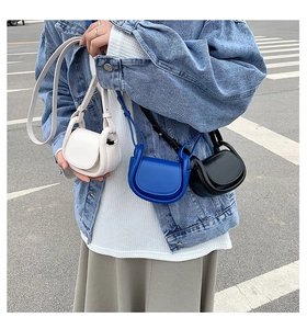 Detail shot of mini saddle crossbody bags in white, blue, and black matte leather textures