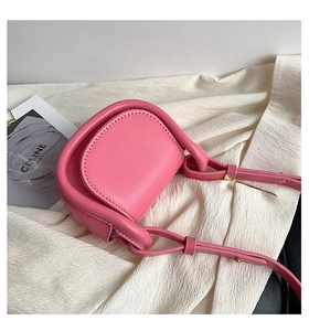 Close-up of a pink mini crossbody saddle bag for girls on soft fabric background