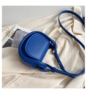 Blue saddle bag for kids made of smooth leather with golden buckles on white fabric