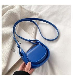 Detail of royal blue leather mini saddle bag with slim shoulder strap and metal buckle