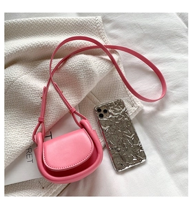 Macro detail of mini pink crossbody bag with padded edges showing a compact flap design