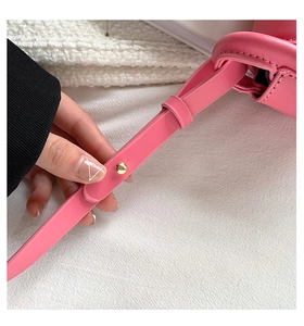 Detail of pink leather handbag strap with gold rivet on textured background