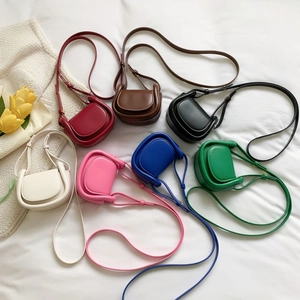 Mini round saddle crossbody bags for kids in seven vibrant colors on white fabric