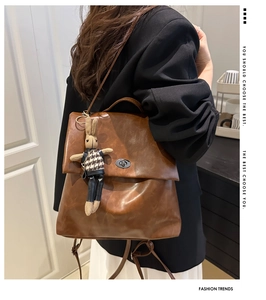 Retro brown leather flap backpack with a metal twist lock and a cute knit bunny charm