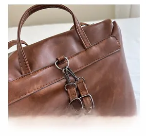 Detail of dark brown leather tote with gunmetal spring hook and adjustable buckles