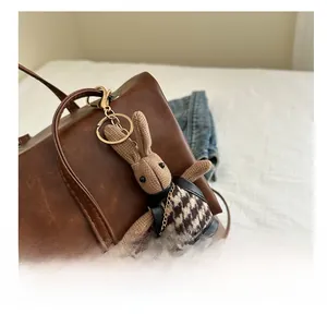 Detail of a khaki knitted bunny charm with houndstooth vest on a leather backpack