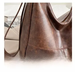 Detalle de la textura agrietada vintage y las costuras de este bolso tote marrón oscuro