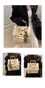 Detail of cream leather backpack with metal turn-lock and cute bunny charm accessory