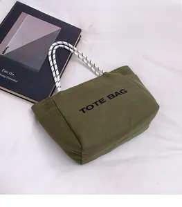 Flat lay of army green canvas tote bag with black rope handles and TOTE BAG lettering