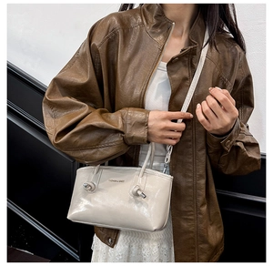 Detail of beige glossy leather tote with metal knots and FASHION & BAGS print