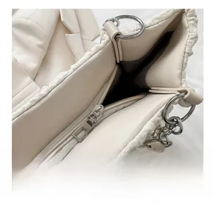 Detailopname van de crème witte pluche handtas met een gladde zilveren metalen rits