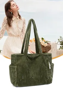 Detail of green corduroy tote bag featuring blue embroidered lettering and soft ribbed texture