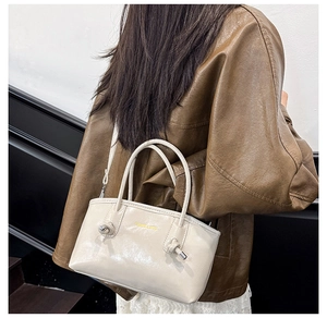 Detail of cream tote bag featuring knot handle design and gold Fashion & Bags lettering