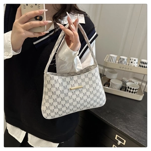 Close-up of a white and grey monogram shoulder bag with gold metal hardware detailing