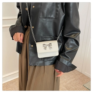 Detailed view of a white mini crossbody bag with a large silver metal butterfly and chain strap