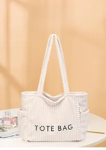 Détail du sac cabas en velours côtelé crème avec texture douce et broderie sur le devant