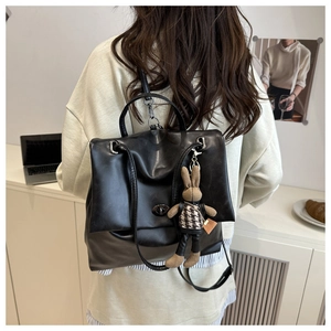 Model showing a black faux leather backpack with a cute bunny charm on the side