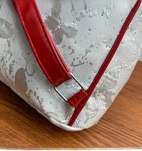 Detail of silver jacquard fabric with dot accents and shiny red leather strap on backpack
