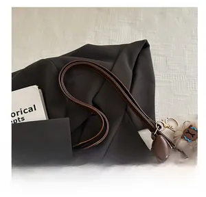 Close-up of brown leather tote bag with metal zipper and cute plush pendant detail